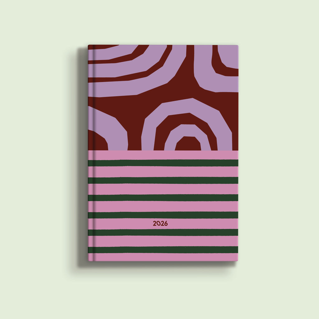 A visually striking A5 diary cover for 2026. The top half features abstract, curved shapes in light purple against a dark red background. The bottom half has horizontal stripes of light pink and dark green. The year "2026" is printed in small pink text on the bottom half.