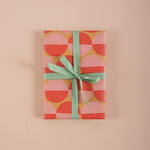 Good Tuesday's eye-catching Peach Sunset recycled wrapping paper, beautifully displayed as eco-friendly gift wrap, designed and proudly made in the UK.