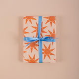 Good Tuesday's vibrant Sunbeam recycled wrapping paper, beautifully displayed as eco-friendly gift wrap, designed and proudly made in the UK.