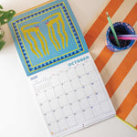 2026 bright and colourful Calendar with a Cat artwork by the artist Ashley. Showing the month of October. 