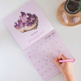 2026 Crystals calendar. 12 month Planner. Image shows calendar open on month of February with an Amethyst crystal design.