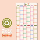 A full-view image of a 2026 pastel compact wall planner in portrait orientation, with a green circle on the left stating "100% RECYCLED PAPER" and text below saying "MADE IN THE U.K." and "PLASTIC FREE PACKAGING."