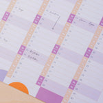 A detailed shot of the lower portion of a 2026 wall planner. Handwritten entries like "Brighton" and "Show - 7pm" are visible, with weekends highlighted.