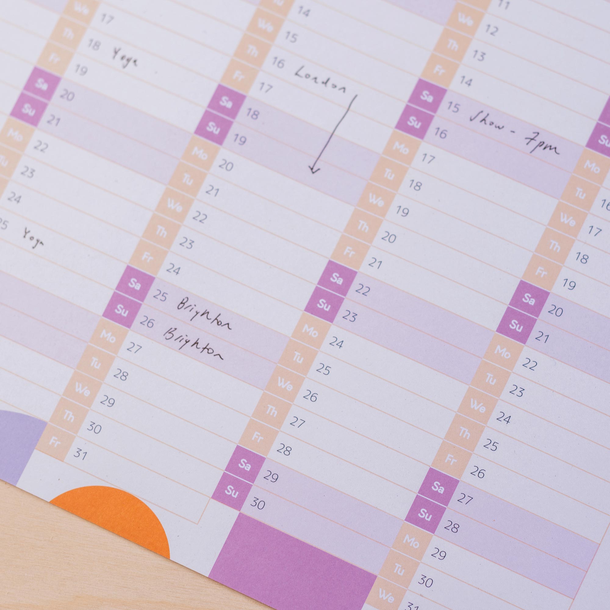 A detailed shot of the lower portion of a 2026 wall planner. Handwritten entries like "Brighton" and "Show - 7pm" are visible, with weekends highlighted.