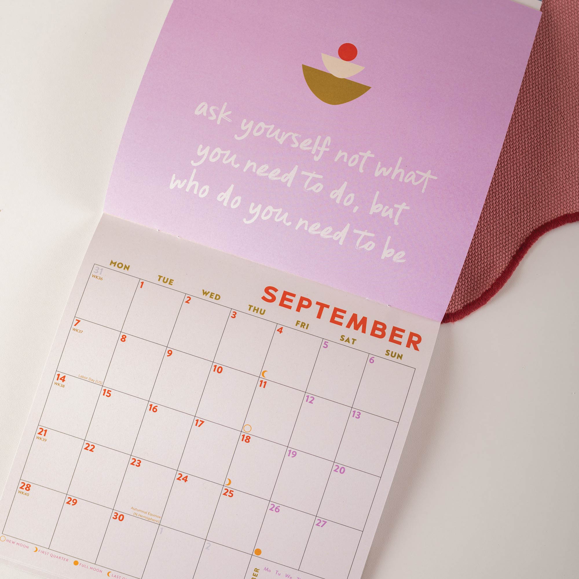 Calendar with September dates on a light surface, featuring motivational quote and colorful design.