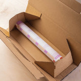 A rolled-up 2026 wall planner, featuring a purple and orange design, shown rolled inside a brown cardboard box, ready for shipping.