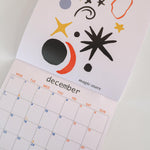 Calendar with abstract designs, showing it open on 'December'.