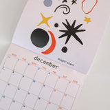 Calendar with abstract designs, showing it open on 'December'.