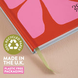 2026 Diary with a pink abstract design on a red cover, featuring a recycled paper label and text about UK manufacturing and plastic-free packaging.