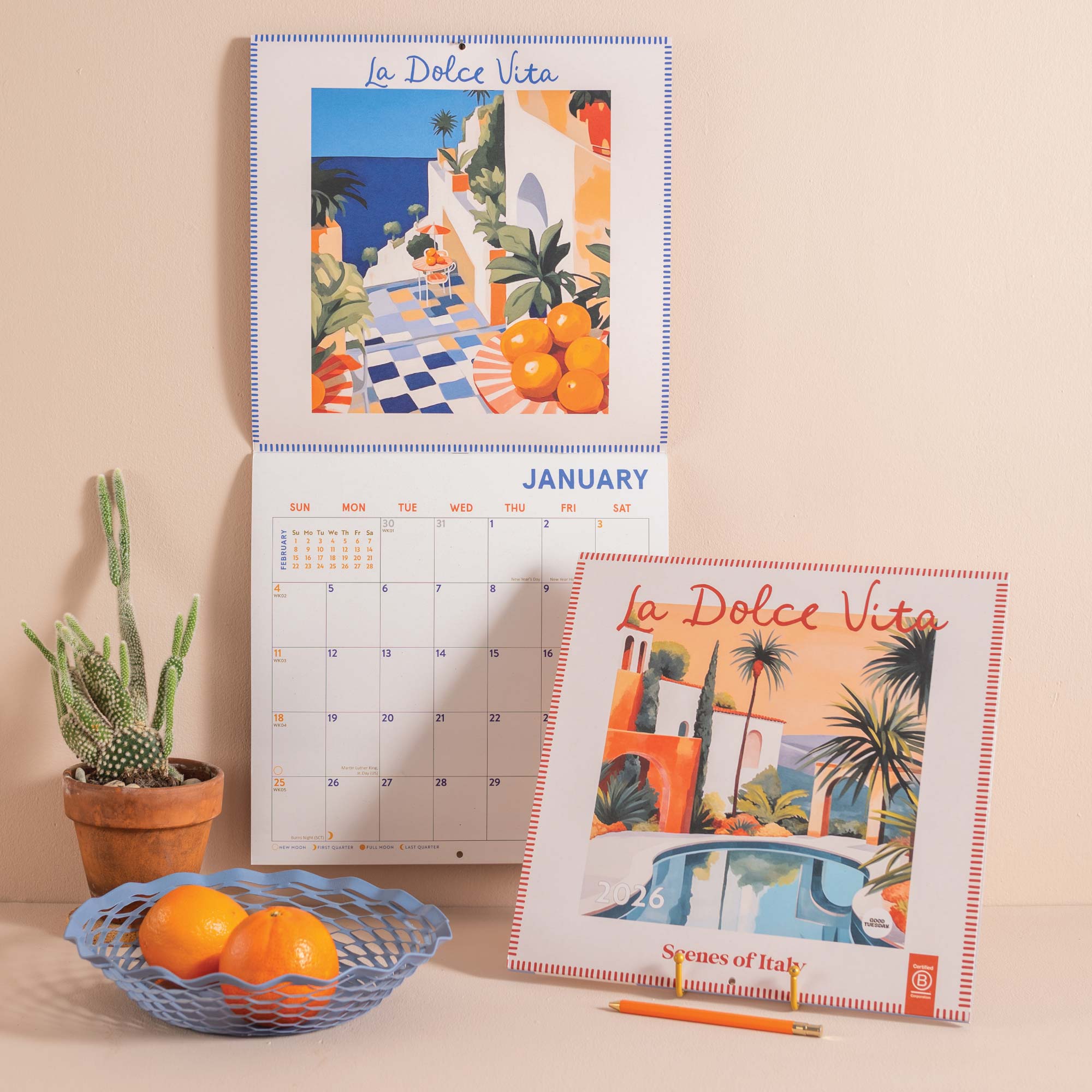 La Dolce Vita calendar with scenic illustrations on a table with oranges and a plant.