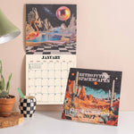 2027 wall calendar with retro futuristic space artwork hanging on the wall.