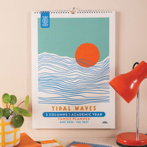 26-27 Academic Calendar with 'Tidal Waves' design on a beige wall next to a lamp and plant