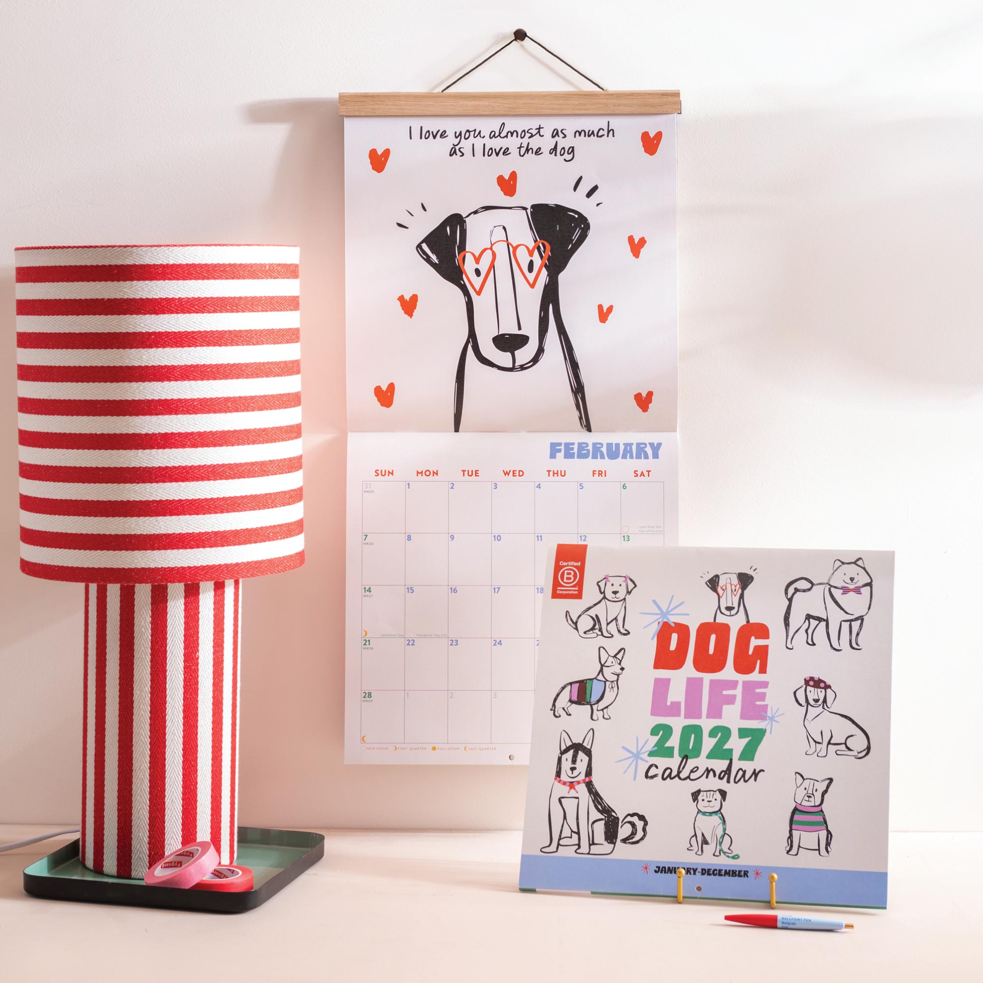 2027 Dog Life wall calendar with playful canine illustrations hanging on wall