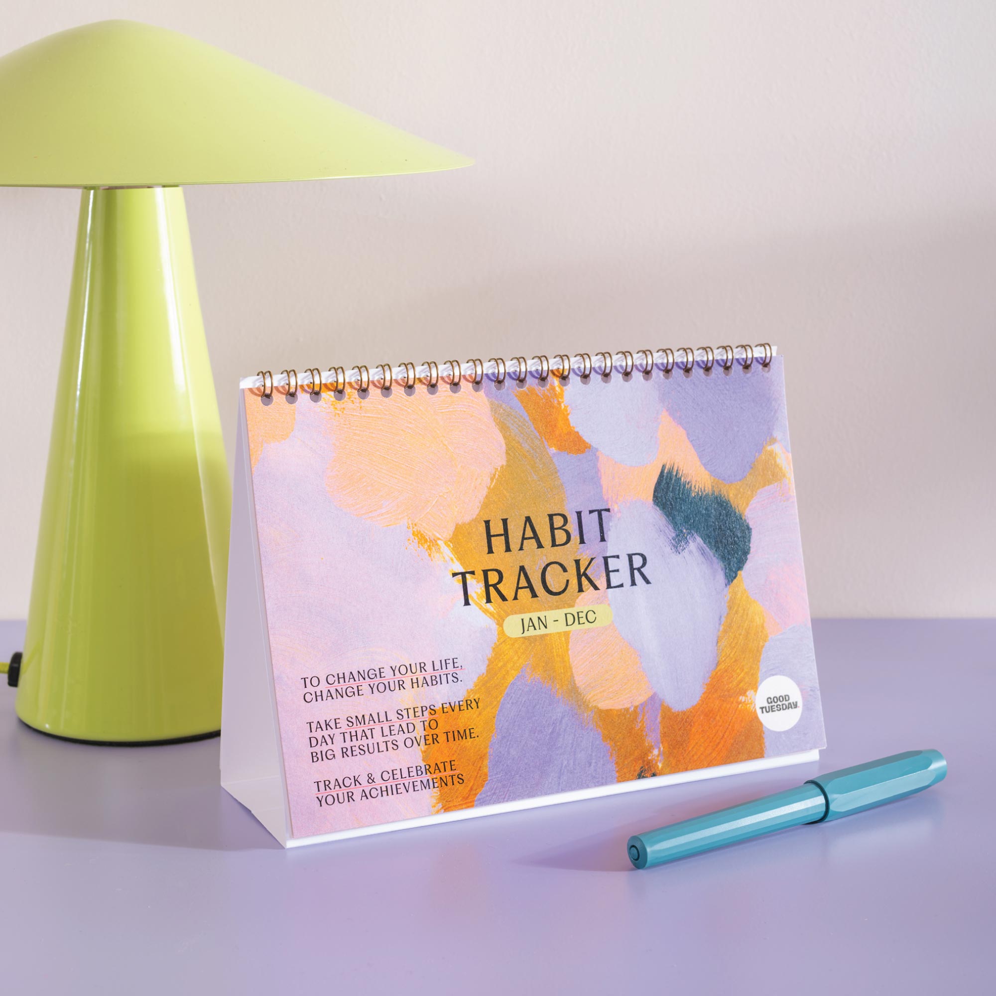 Habit tracker calendar on a table with a green lamp in the background