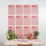 Large Monthly Undated A3 Wall Planner – 12 pink and red monthly pages displayed on a wall above a desk with decorative items