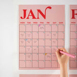 Close-up of January page from the pink and red A3 wall planner, featuring bold typography and handwritten notes
