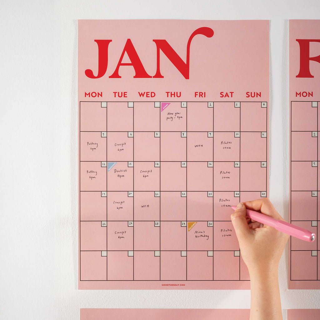 Close-up of January page from the pink and red A3 wall planner, featuring bold typography and handwritten notes