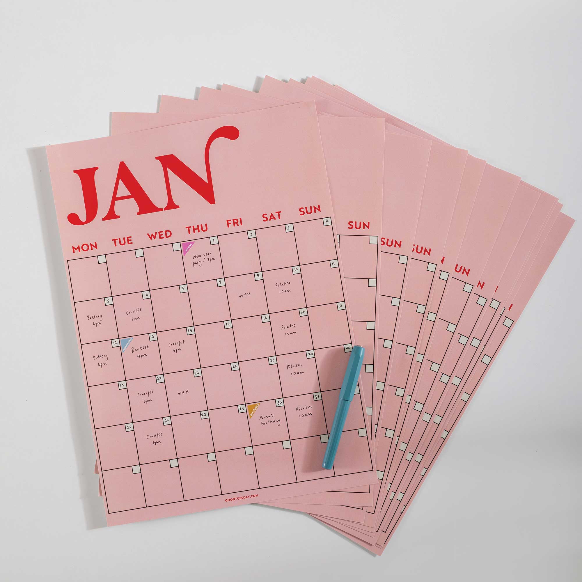 Spread of all 12 monthly pages from the pink and red A3 wall planner laid out on a surface