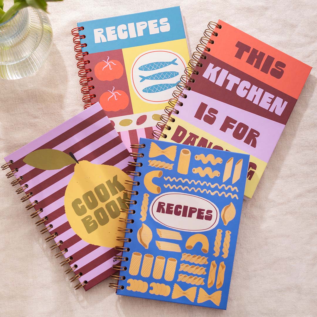 Four colourful blank recipe journals on a light surface