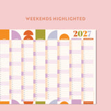 Compact geometric citrus splash wall planner for 2027 with weekends highlighted on a pink background