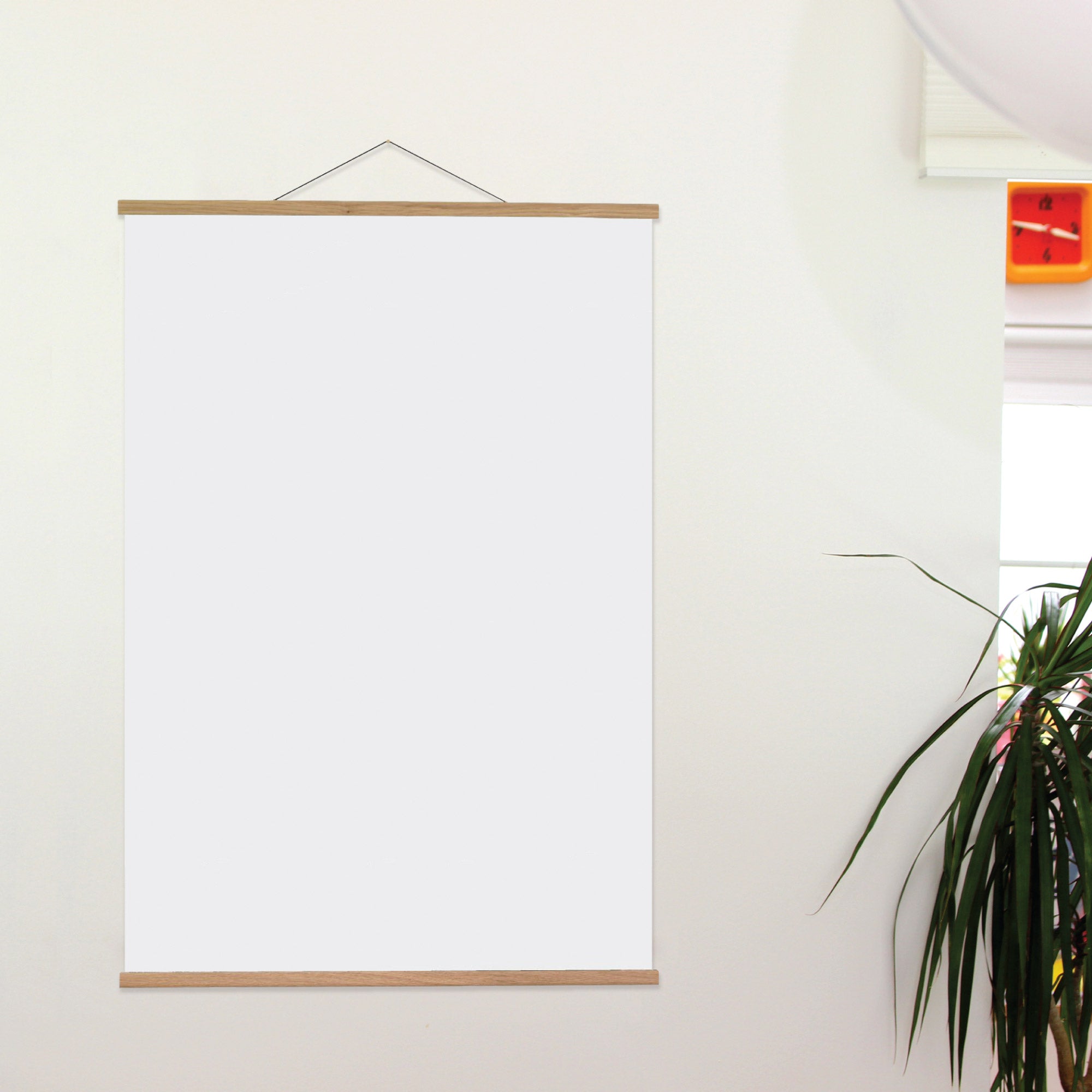 White frame with wooden border on a white wall with a plant in the corner.