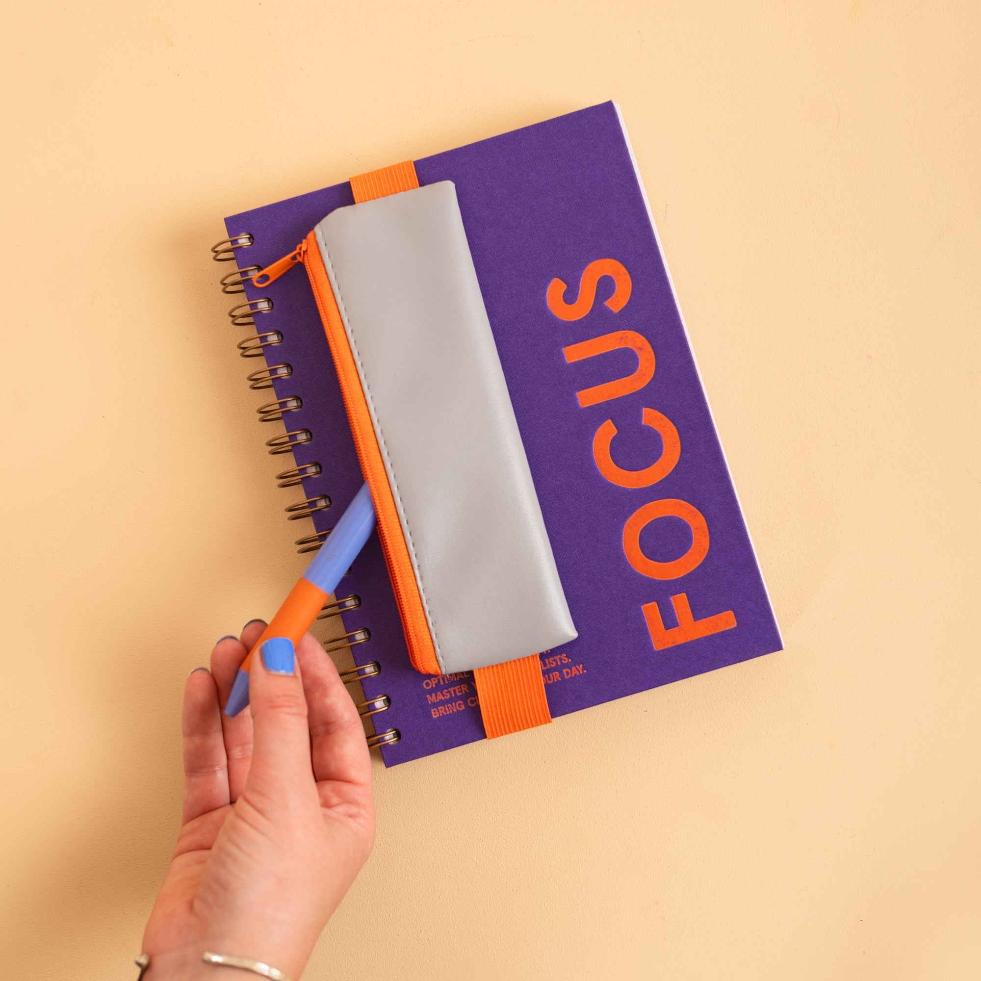 Elastic band stretches around a standard notebook to hold the Grey pencil pouch in place