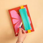 Elastic band stretches around a standard notebook to hold the Turquoise pencil pouch in place