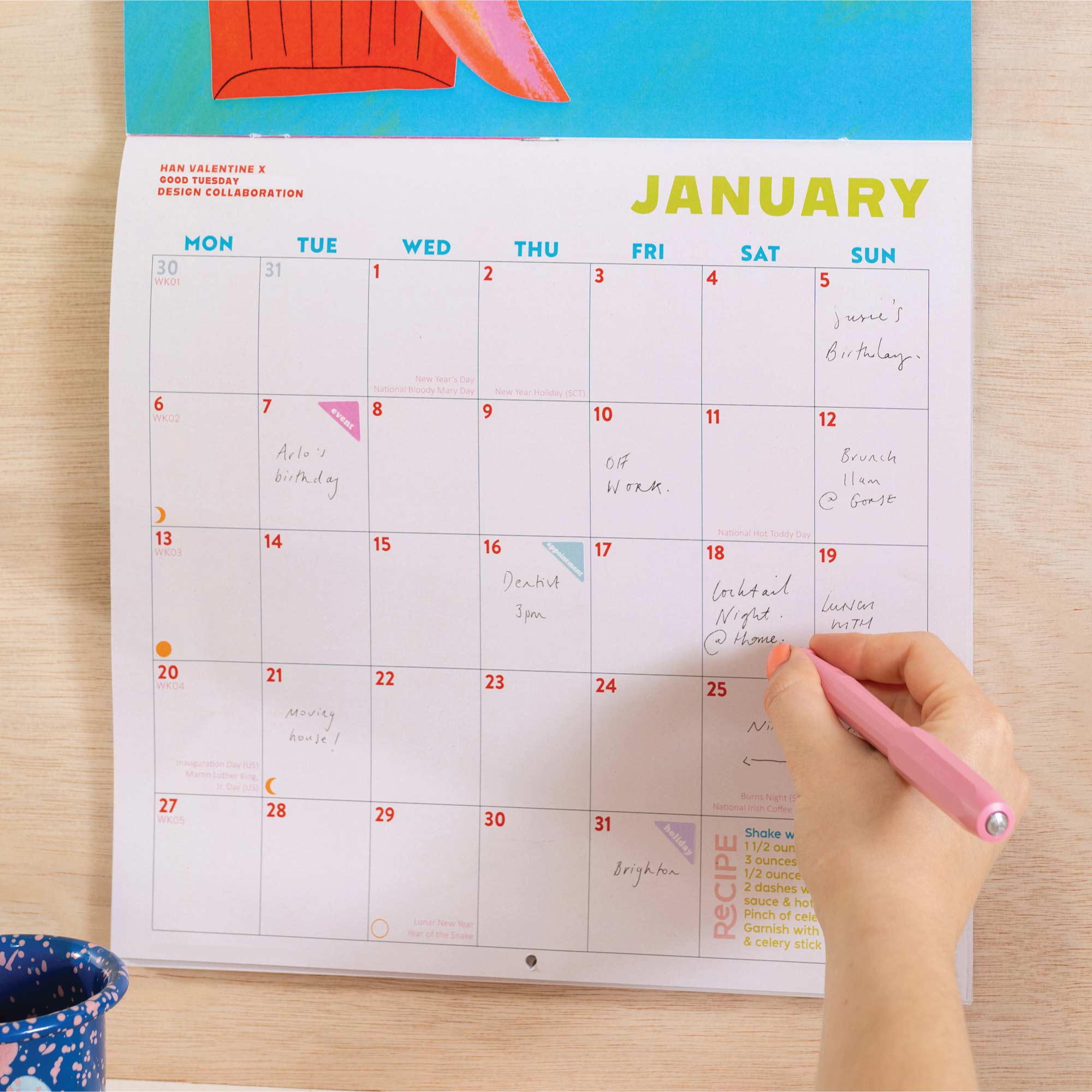 Close up of Cocktails 2026 calendar, showing the planner in use. Large monthly grid with week numbers, bank holidays, lunar phases, and recipe.