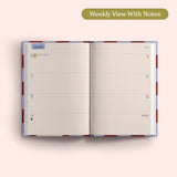 Open planner showing a weekly view with notes on a pink background. Recycled Paper.