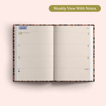Open planner showing a weekly view with notes on a pink background. Recycled Paper.
