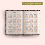 Open planner showing 2027 and 2028 yearly overview on a pink background.