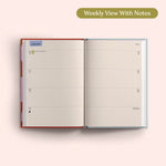 Open planner showing a weekly view with notes on a pink background. Recycled Paper.