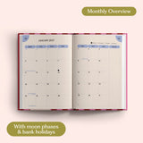Open planner showing month-to-view January 2027 with moon phases and bank holidays on a pink background.