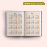 Open planner showing 2027 and 2028 yearly overview on a pink background.