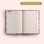 Open planner showing a weekly view with notes on a pink background. Recycled Paper.