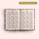 Open planner showing 2027 and 2028 yearly overview on a pink background.