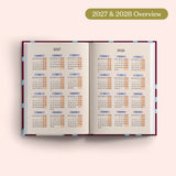 Open planner showing 2027 and 2028 yearly overview on a pink background.