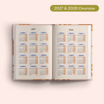 Open planner showing 2027 and 2028 yearly overview on a pink background.