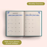 Open planner showing month-to-view January 2027 with moon phases and bank holidays on a pink background.