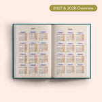 Open planner showing 2027 and 2028 yearly overview on a pink background.