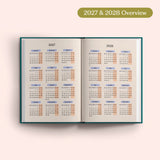 Open planner showing 2027 and 2028 yearly overview on a pink background.