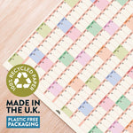 Colorful grid pattern on paper with a recycling logo and text about recycled paper and plastic-free packaging.
