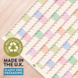 Colorful grid pattern on paper with a recycling logo and text about recycled paper and plastic-free packaging.