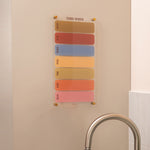 Wipeable weekly acrylic planner with spacious daily layout in an earthy colour palette mounted on a wall 