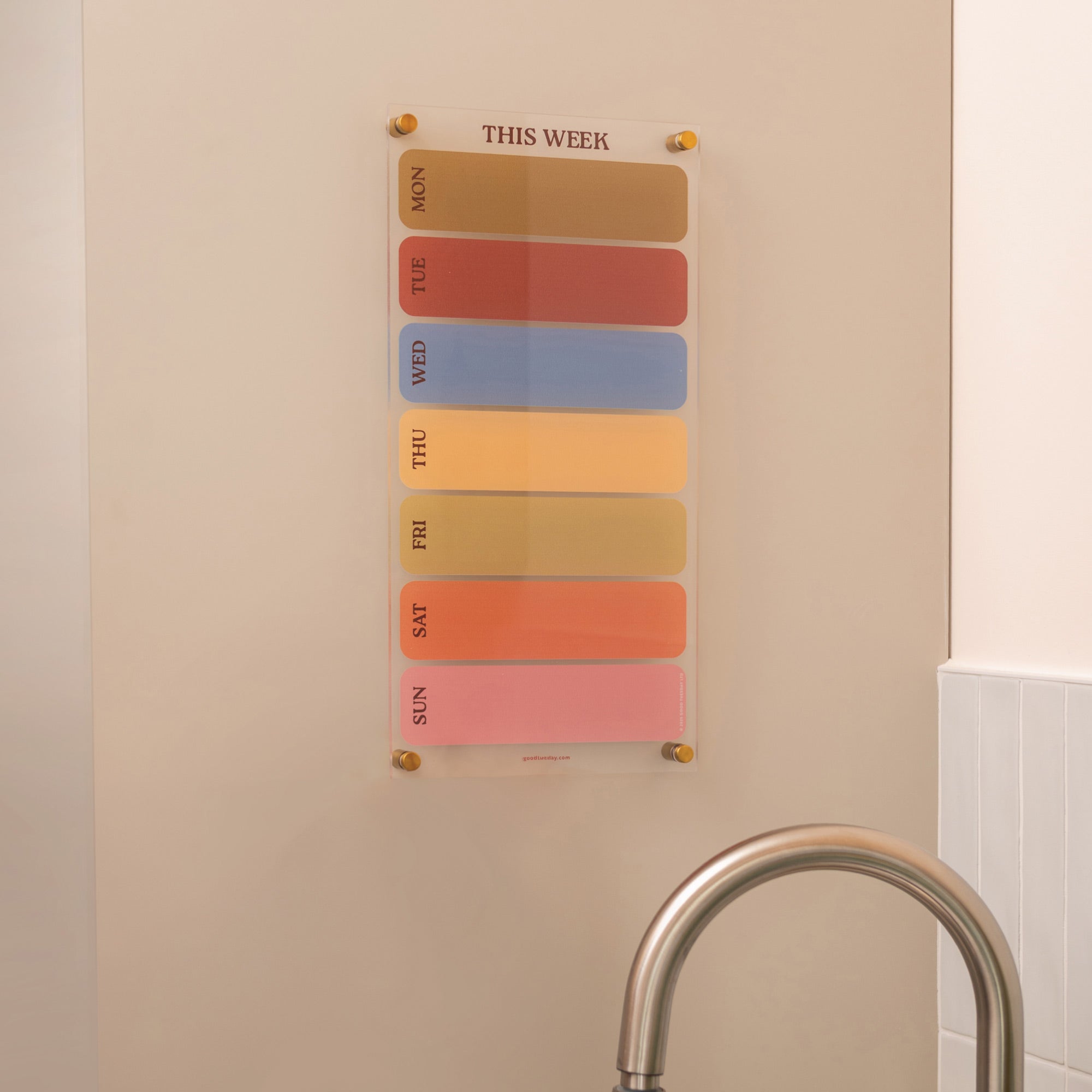 Wipeable weekly acrylic planner with spacious daily layout in an earthy colour palette mounted on a wall 