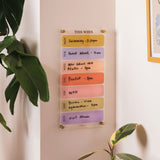 Wipeable weekly acrylic planner mounted on wall in use for organising weekly plans