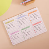 A printed checklist planner insert titled "THE LISTS" with six colored sections for separate lists on a peach background with a small wooden block and pen visible.
