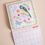 Close up of whimsical folk-style songbird artwork on 2027 wall calendar