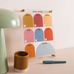 Wipeable weekly planner propped on a wall in use for organising weekly schedule