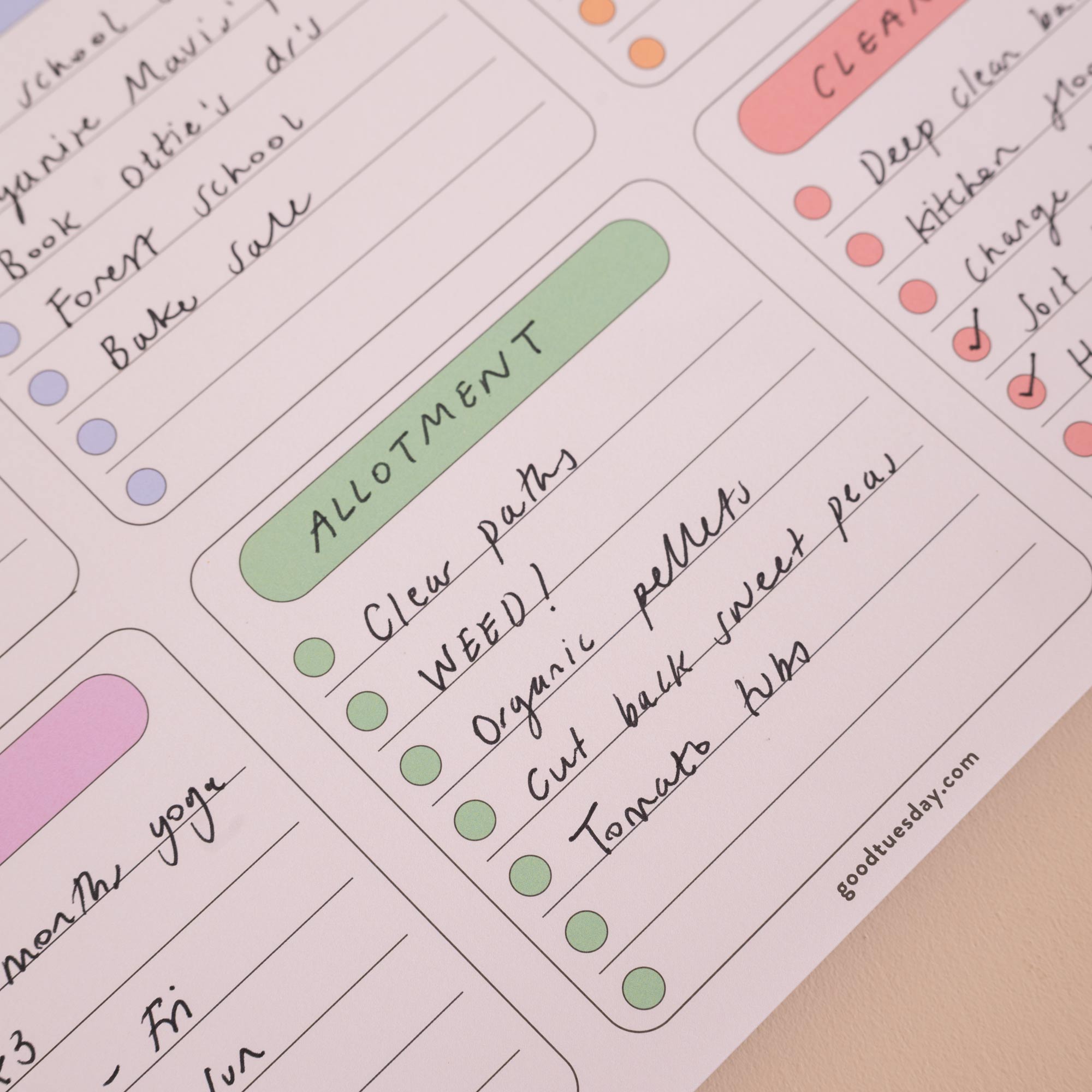 A close-up of a printed weekly planner or task tracker sheet with pastel-colored headers and handwritten notes, photographed on a light neutral surface.